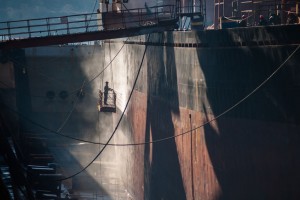 58969922 - shipyard worker power washing a ship on dry dock